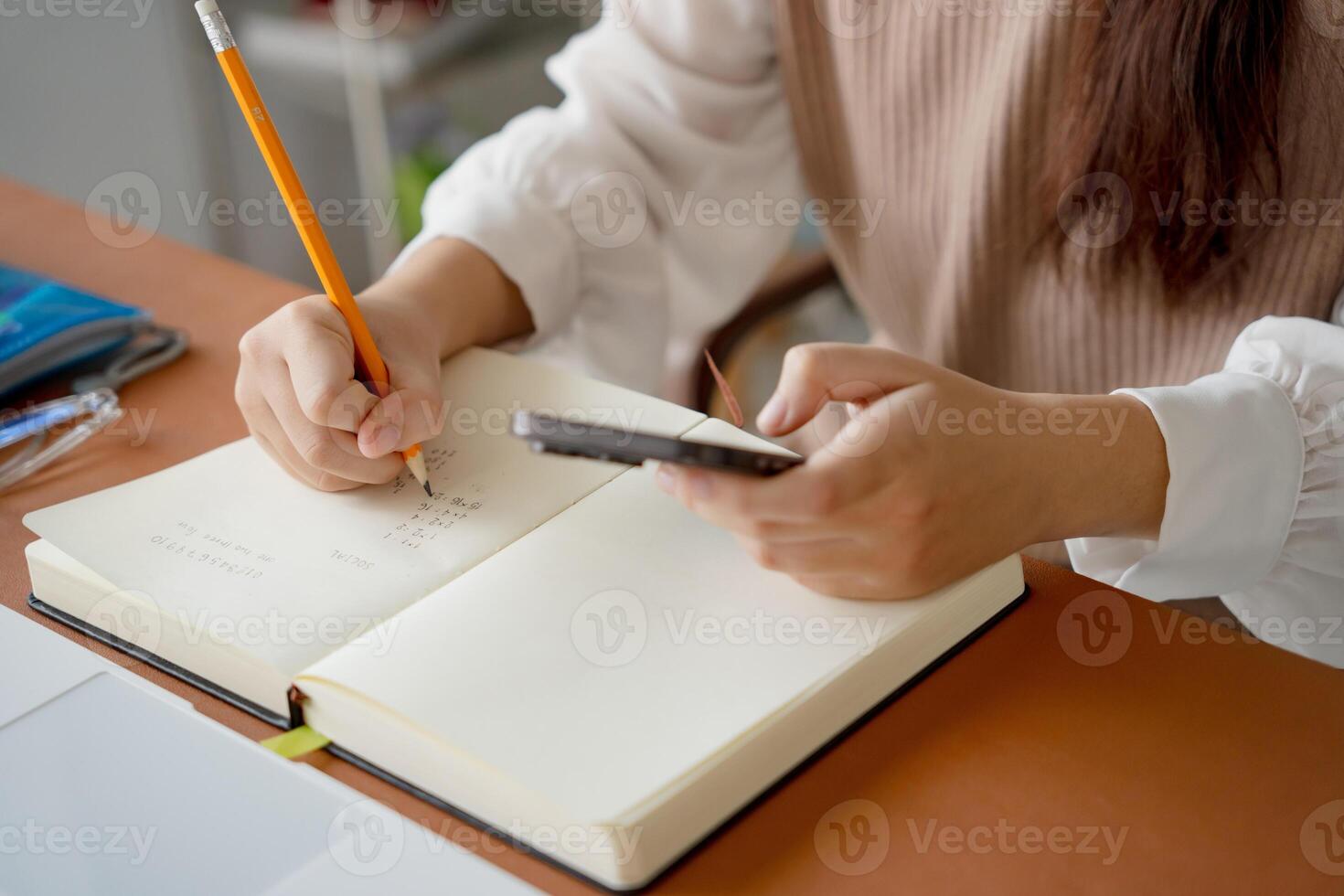 a woman is writing in a notebook with a pencil photo