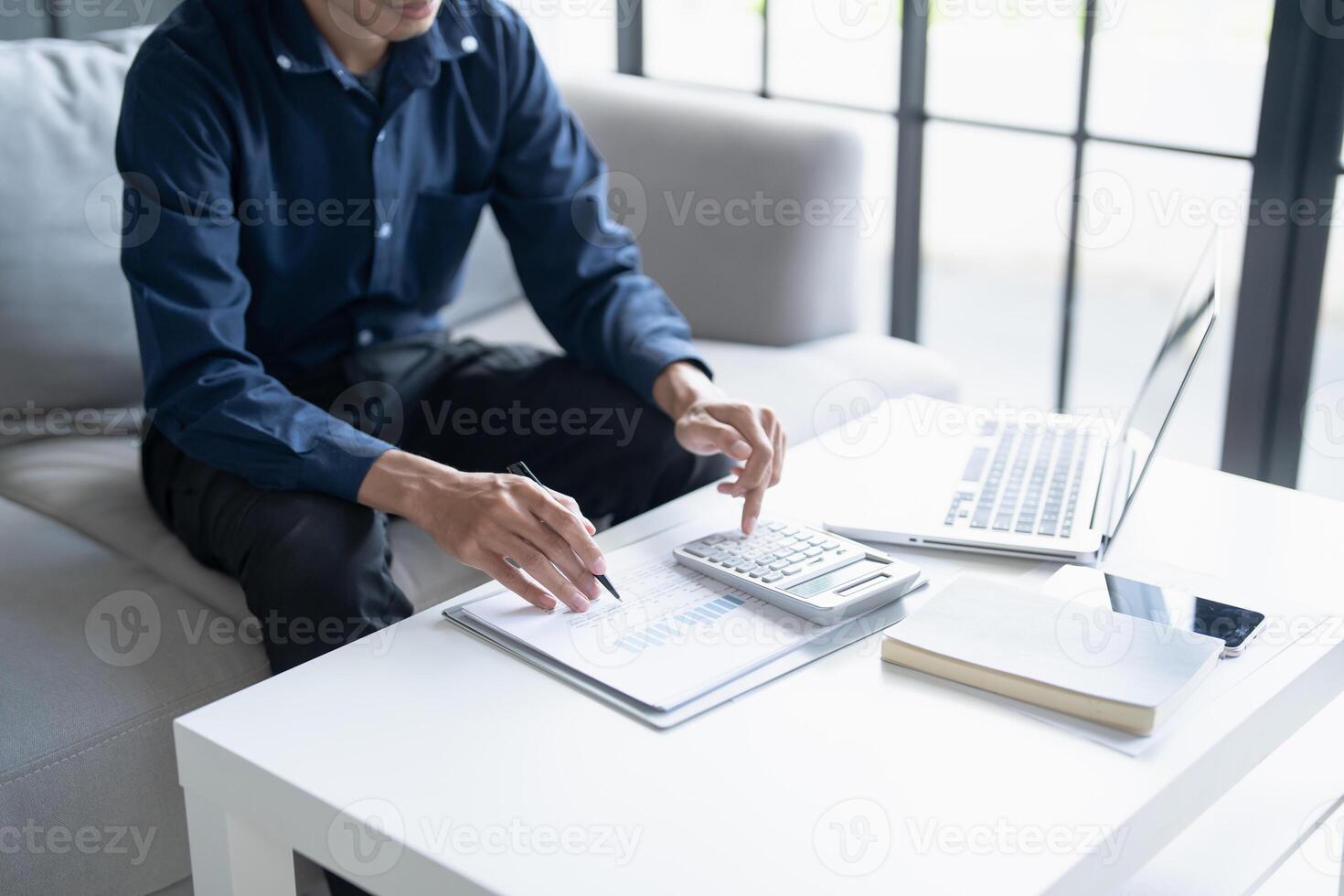 a man sitting on a couch with a laptop and a calculator photo