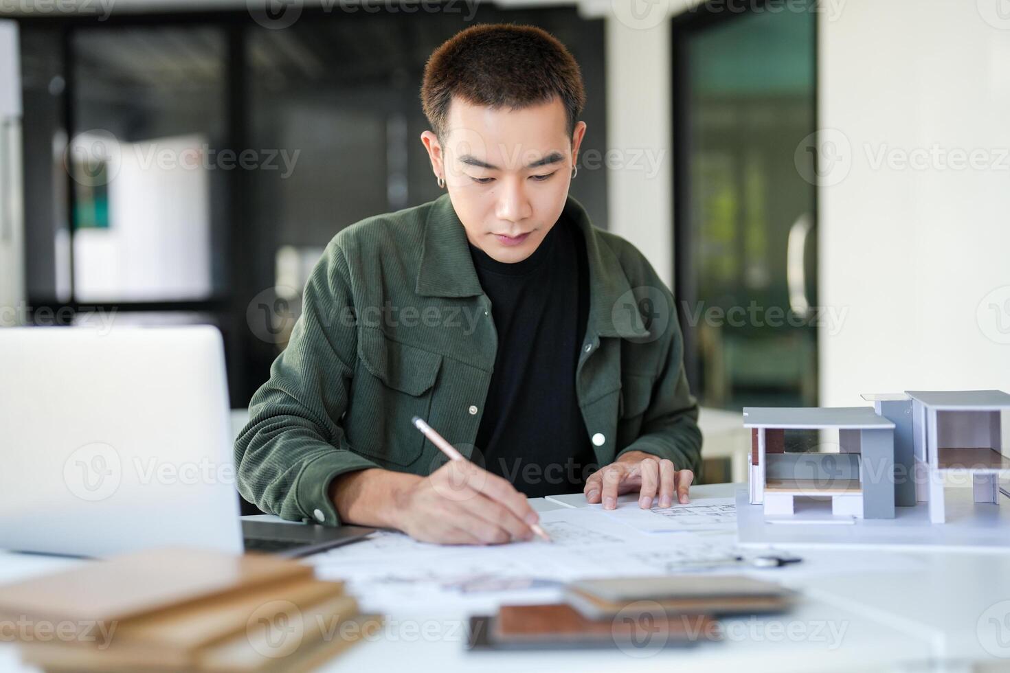 a man is working on a project with a laptop and a pencil photo