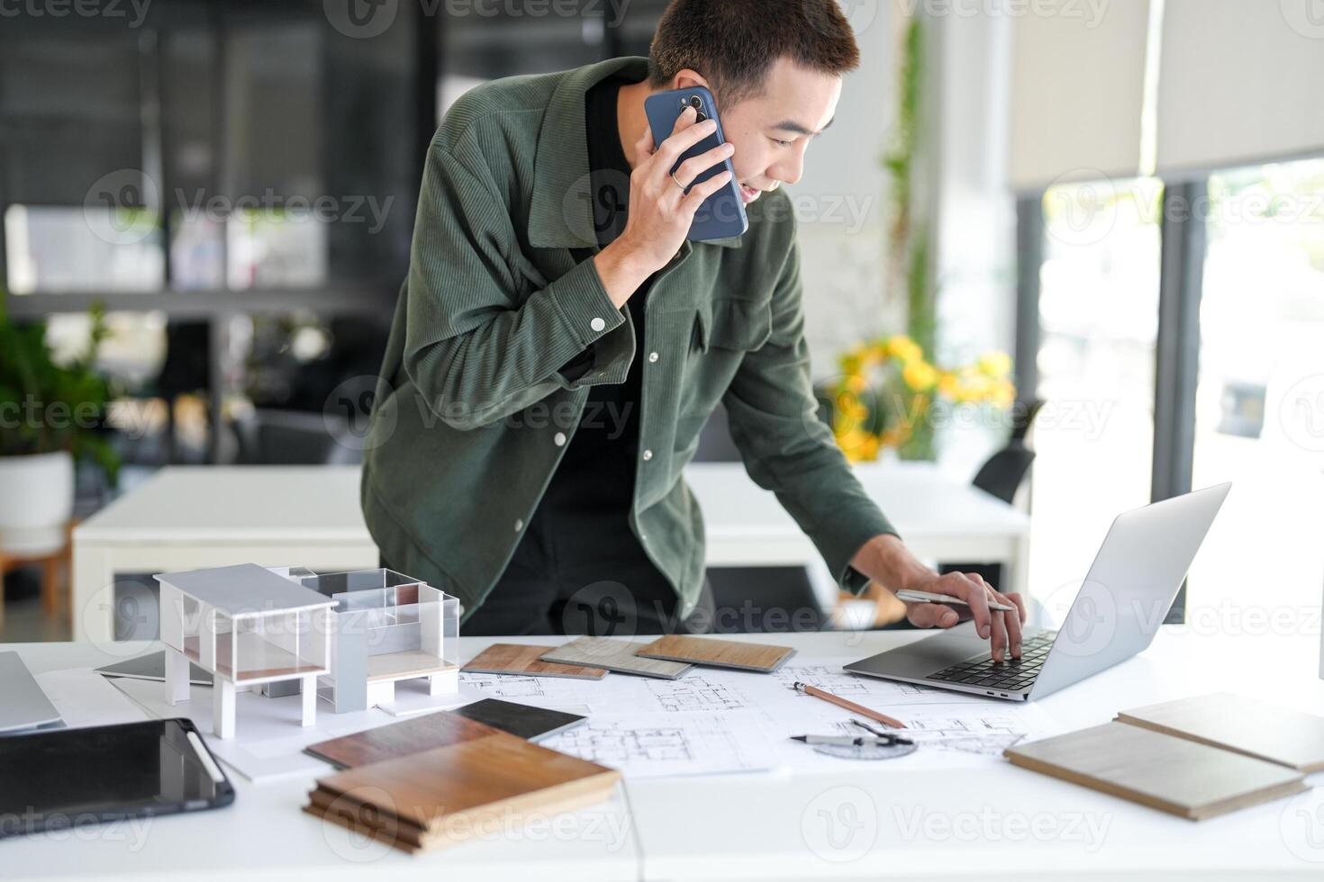 a man is talking on the phone while working on a laptop photo