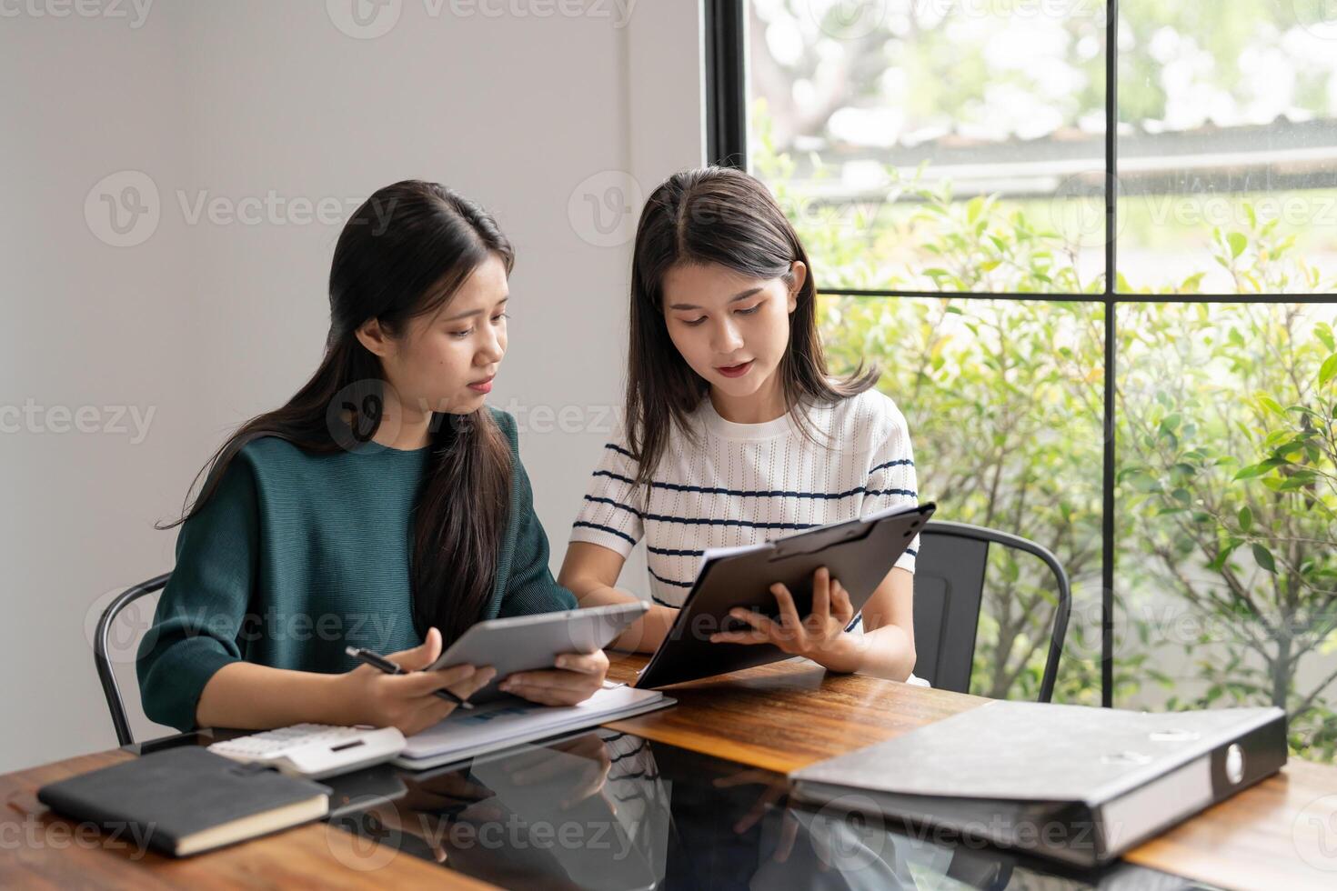 two two women sitting at a table with a tablet in office photo