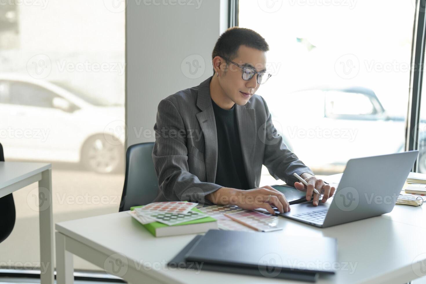 Asian Businesman Creative Designer sketch graphic drawing on graphic laptop and Color swatch samples of idea creativity photo