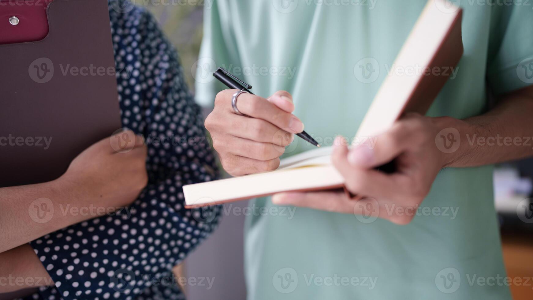 a man and woman holding a pen and writing on a book photo