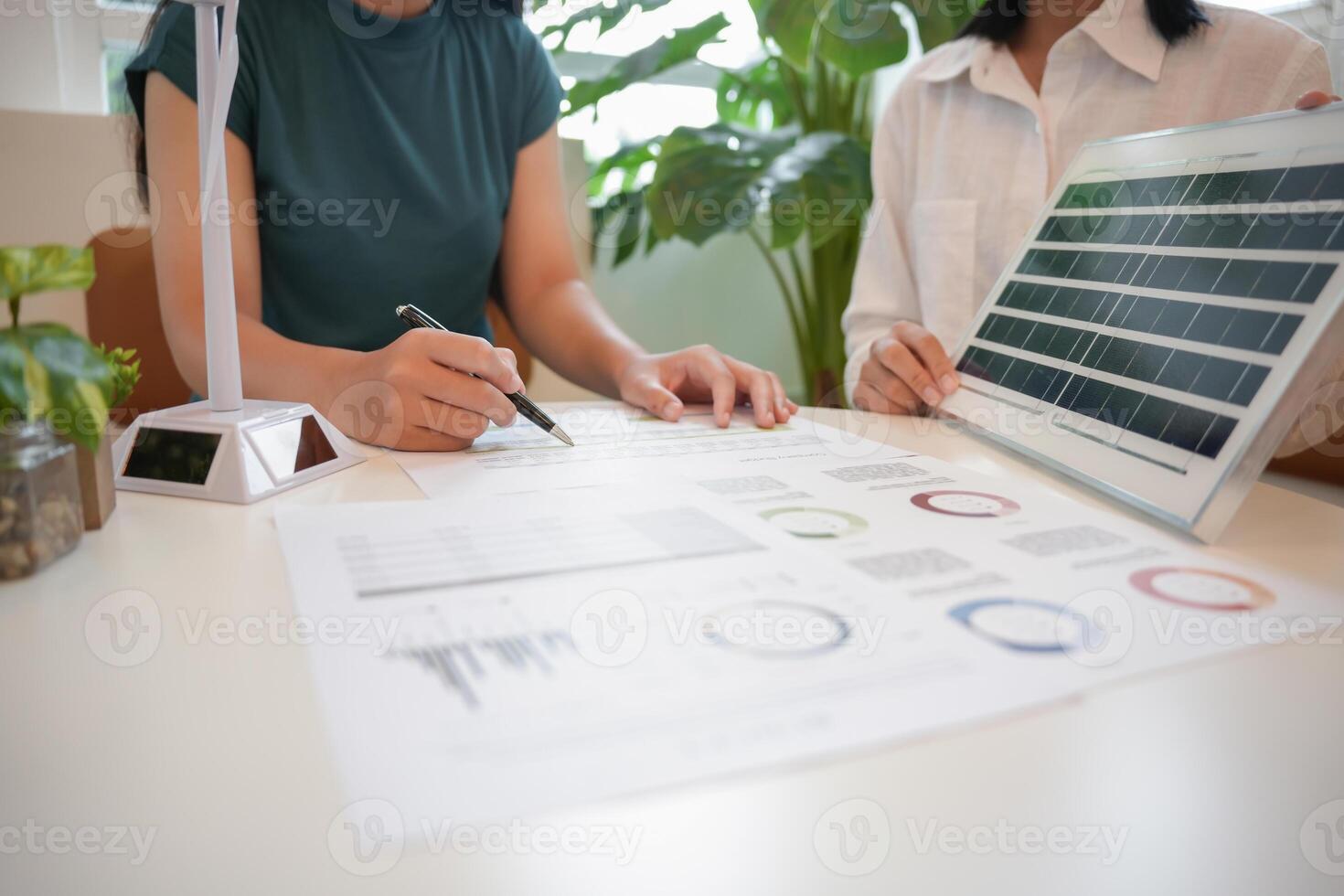 two women at a table with solar panel and papers photo
