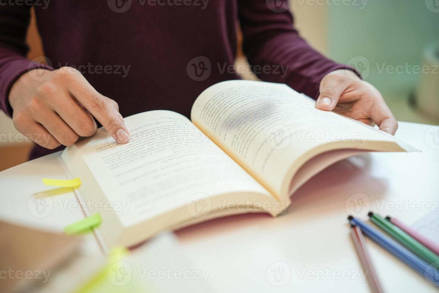 Young female student studying and writing on notebook making in school library. photo