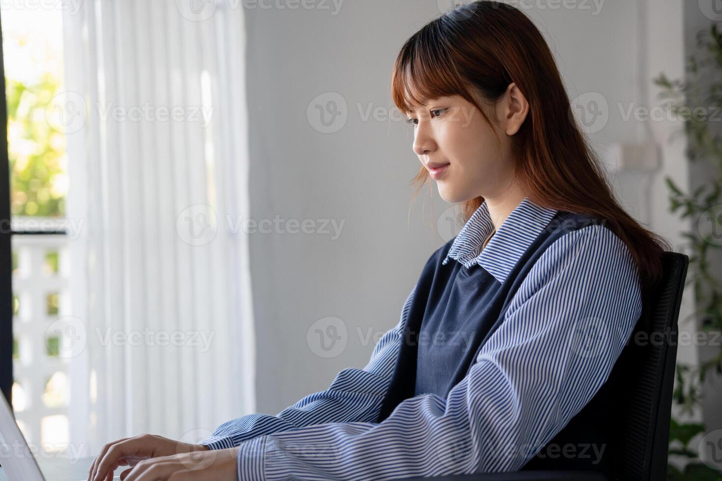 asian woman working on laptop in office photo