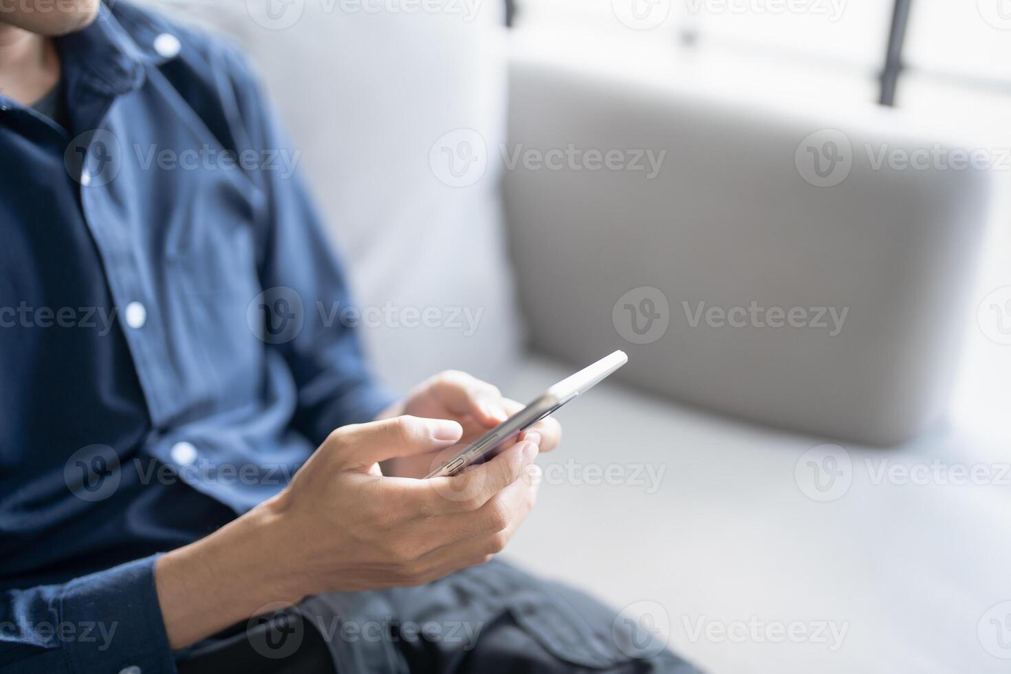 Relaxed asian man using smart phone spending time checking social media photo