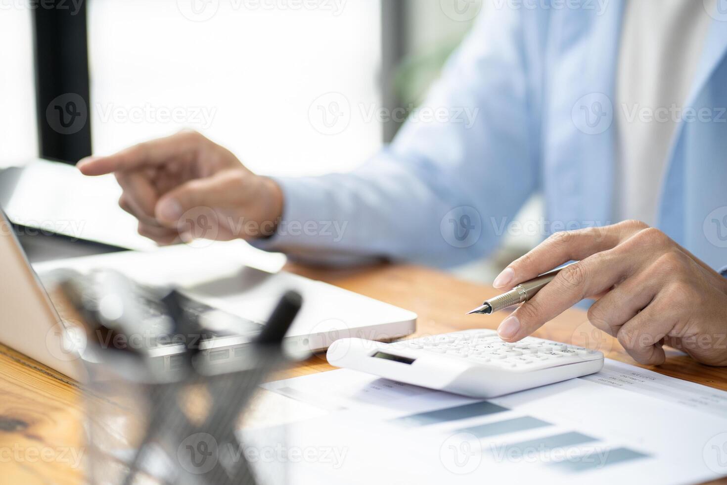 a person is using a calculator and pen on a laptop photo