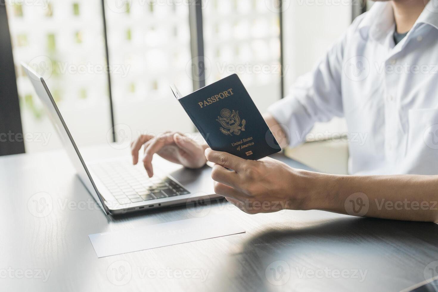man using laptop and passport in office photo