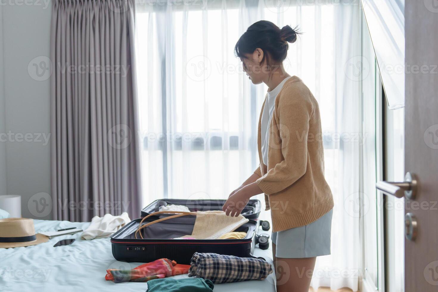 Woman packing suitcase on bed for a new journey photo