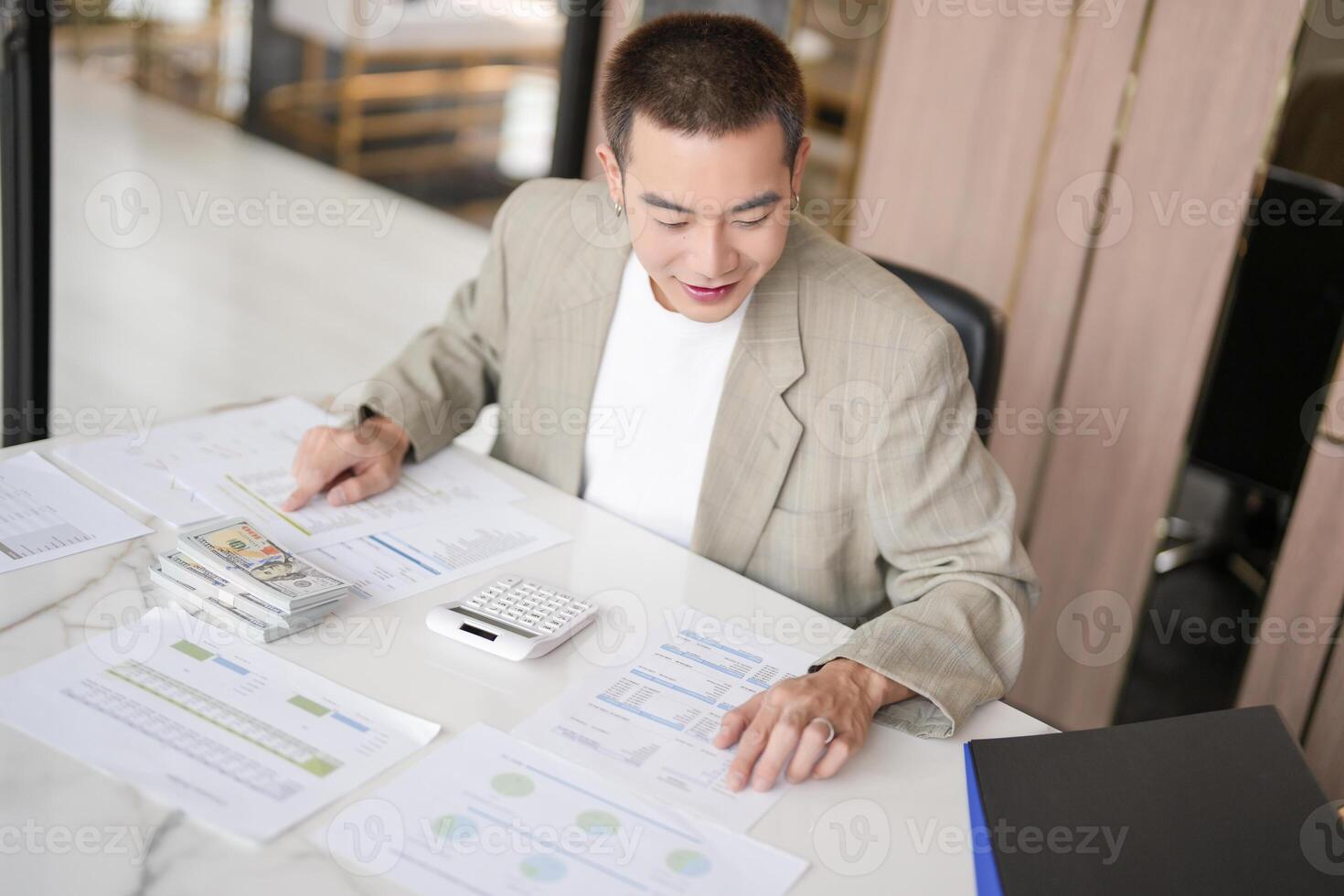 a man in a suit sitting at a table with papers photo