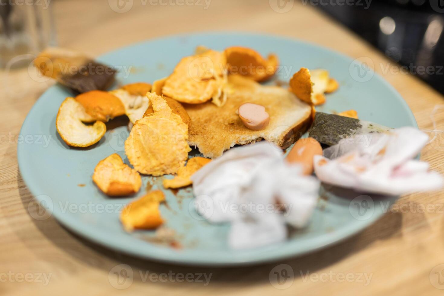 Dirty kitchen plate with leftovers and trash near sink and utensils. Household mess and unclean habits in a neglected domestic environment. photo