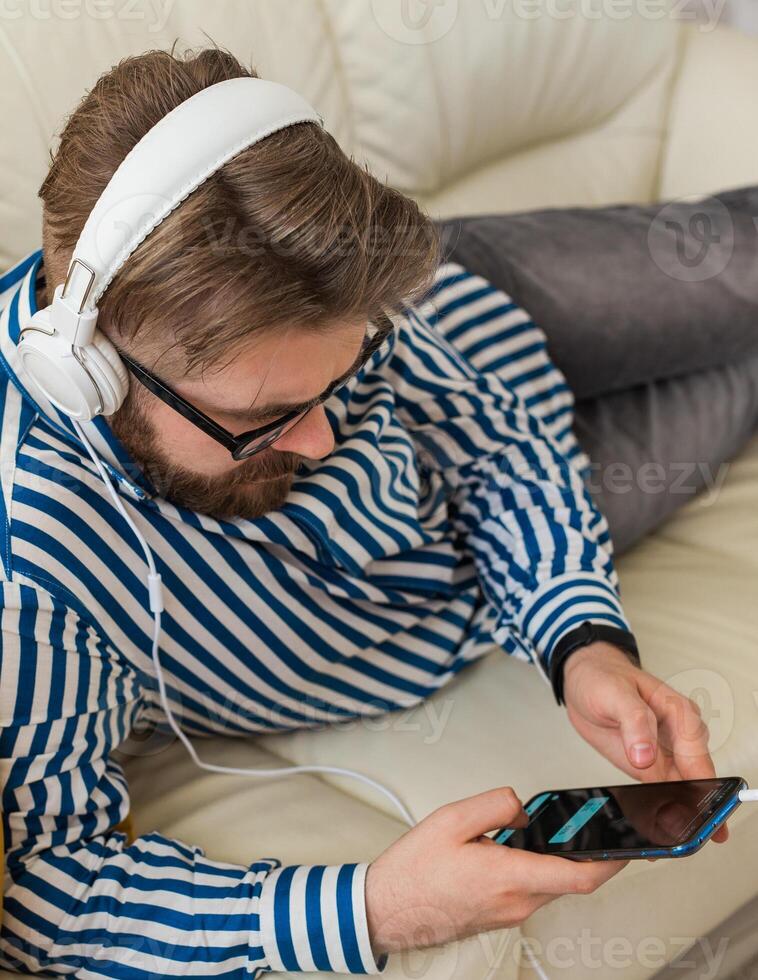 Man relaxing with smartphone and headphones at home. Music, communication and modern digital lifestyle concept photo