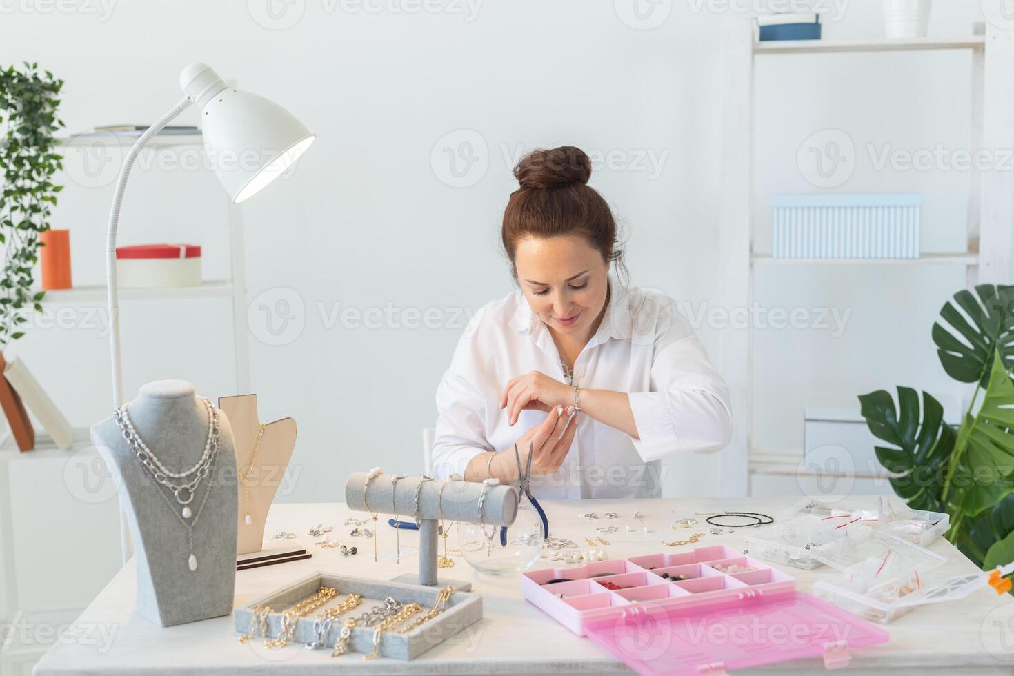Professional happy accessories designer making handmade jewelry in studio workshop. Fashion, creativity and handmade concept. photo
