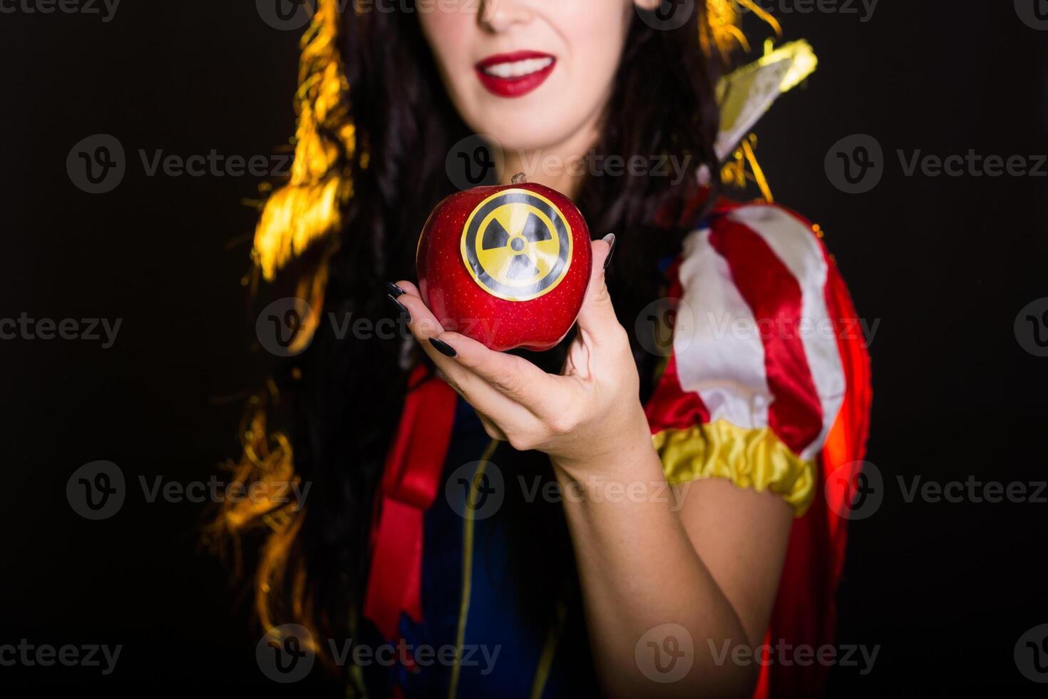 Close-up girl dressed as fairytale character holds Radioactive atomic nuclear ionizing radiation danger warning symbol on apple. Nuclear and radiation measurement concept. photo