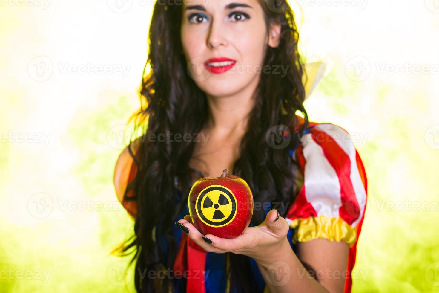 Close-up female wearing a fairy tale dress holding an apple with radiation symbol. Environmental problems concept, radioactive disaster as danger on nature. photo