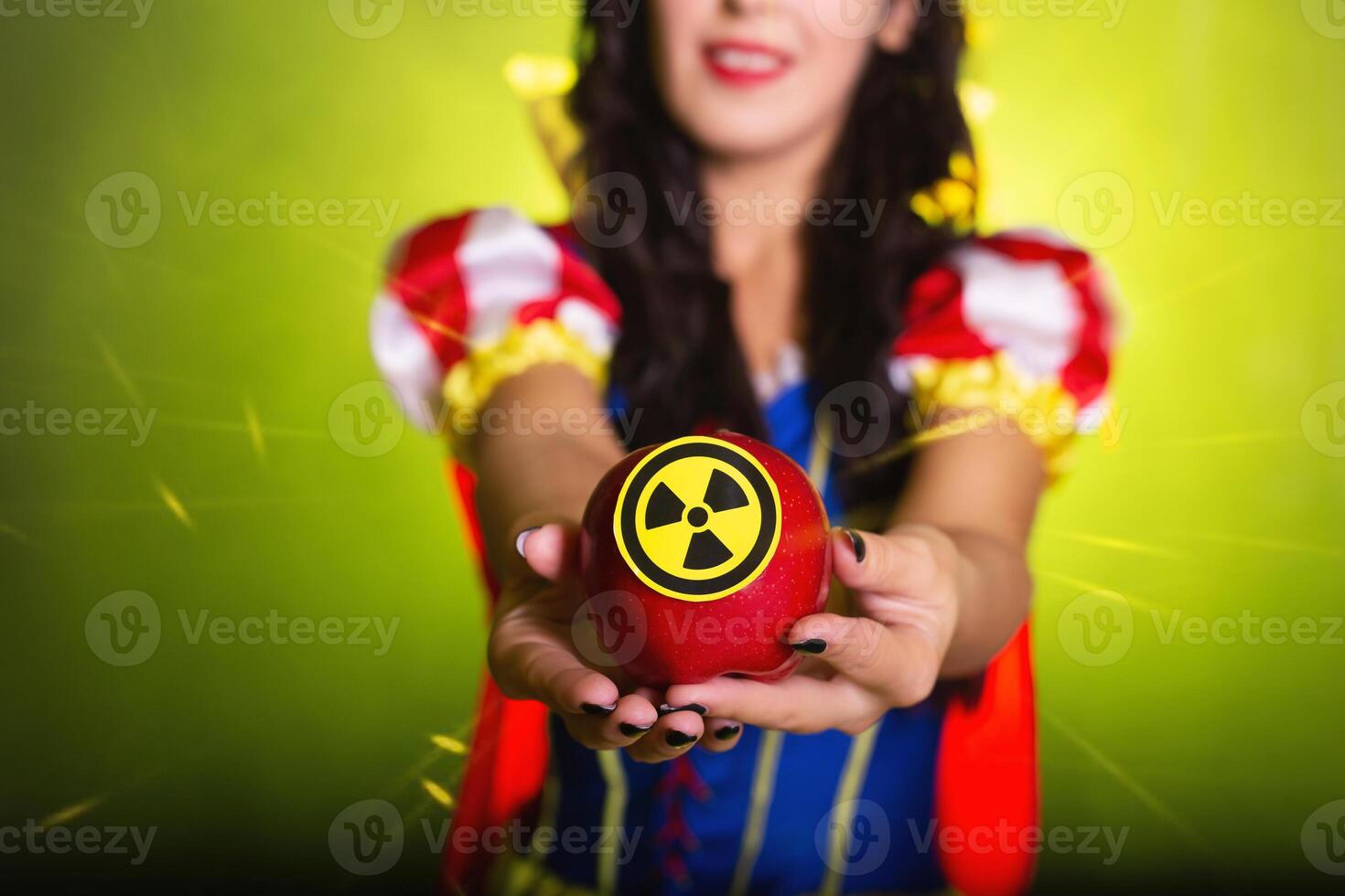 Woman dressed as Snow White holds Radioactive atomic nuclear ionizing radiation danger warning symbol on apple. Nuclear concept. photo