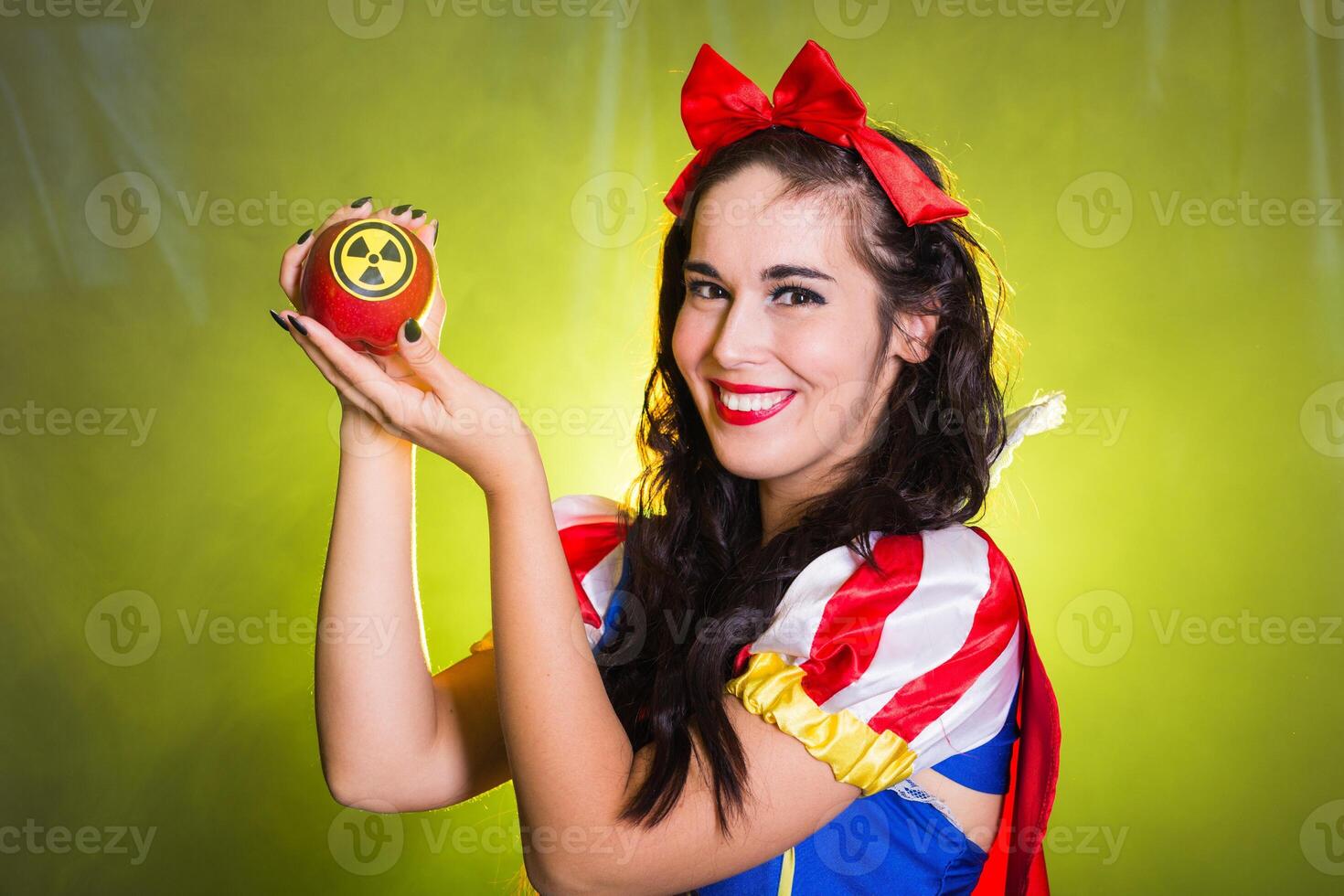 Funny girl wearing a fairy tale dress holding an apple with radiation symbol. Environmental problems concept, radioactive disaster as danger on nature. photo