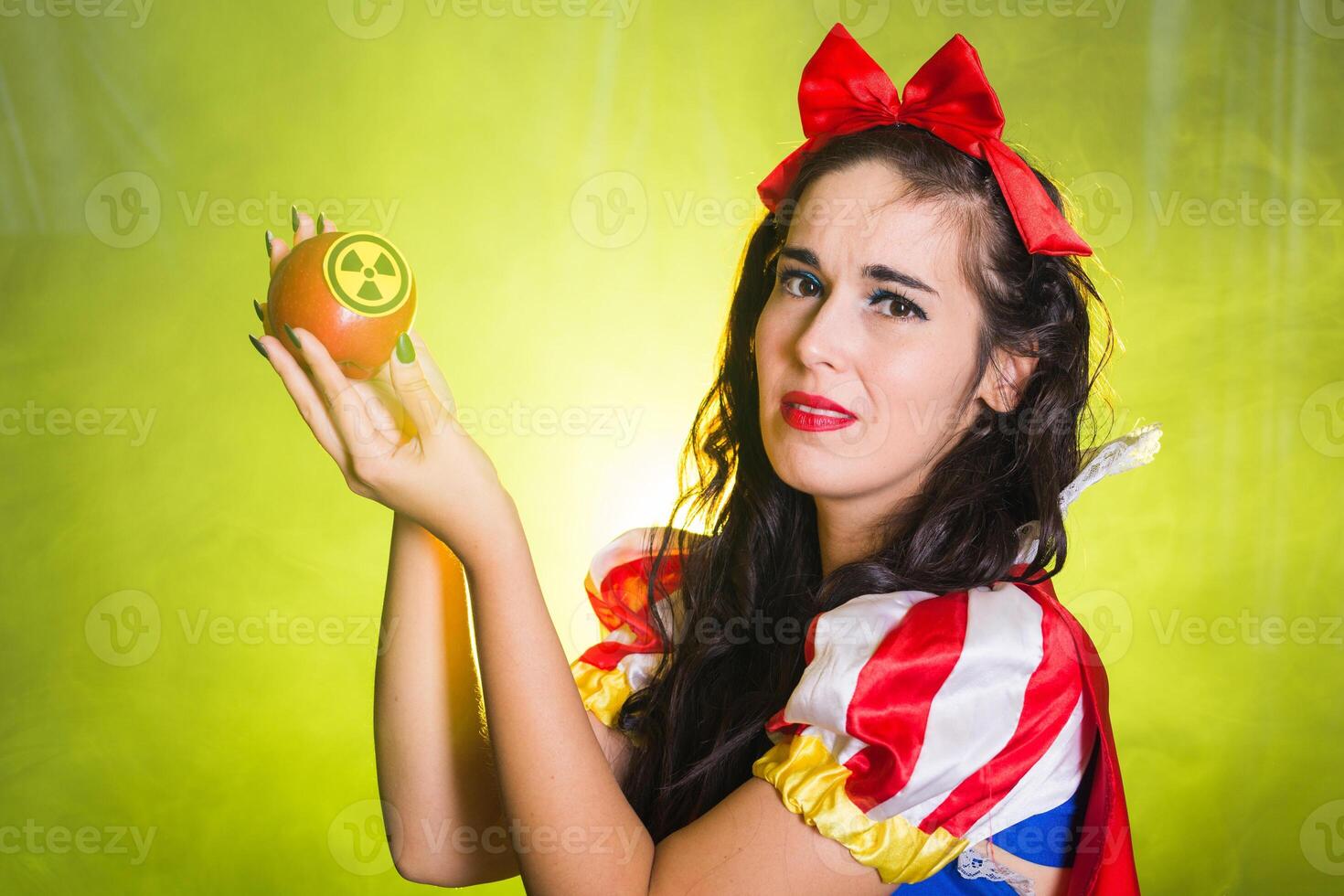 Close-up of sad Woman wearing a fairy tale dress holding an apple with radiation symbol. Environmental problems concept, radioactive disaster as danger on nature. photo