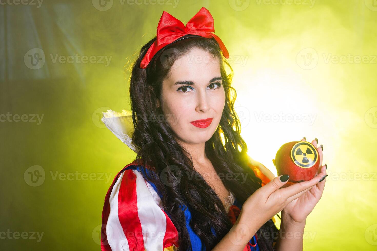 Close-up Woman wearing a fairy tale dress holding an apple with radiation symbol. Environmental problems concept, radioactive disaster as danger on nature. photo