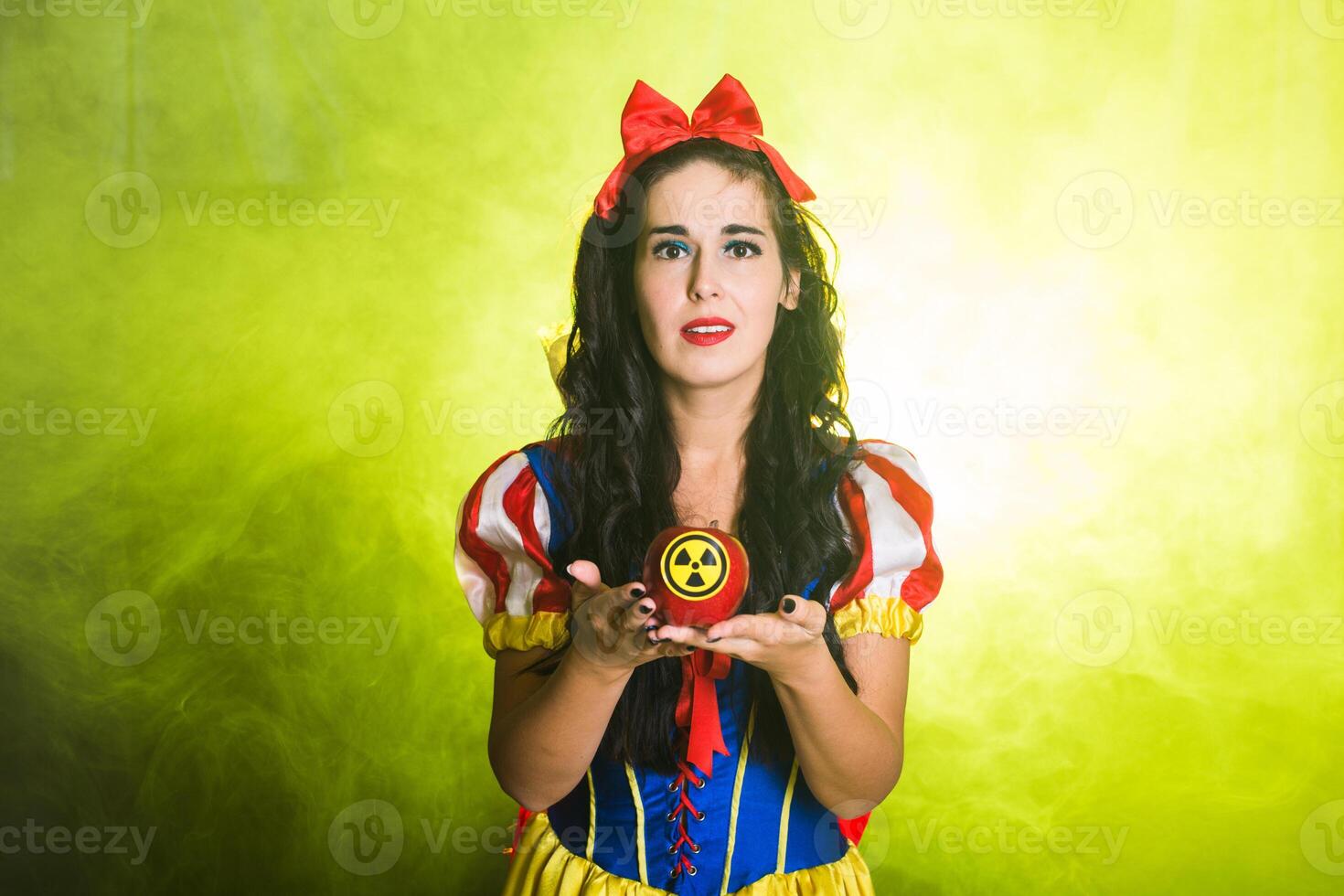 Sad girl dressed as fairytale character holds Radioactive atomic nuclear ionizing radiation danger warning symbol on apple. Nuclear and radiation measurement concept. photo