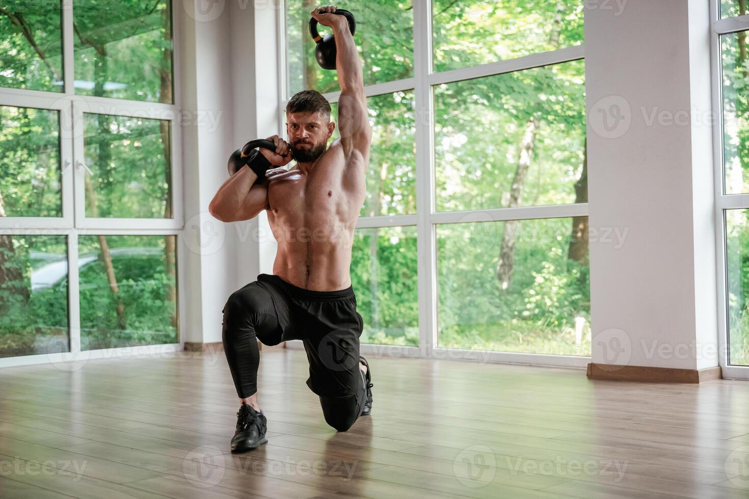 Against the, windows.. With dumbbells. Strong muscular man is working out in the gym photo