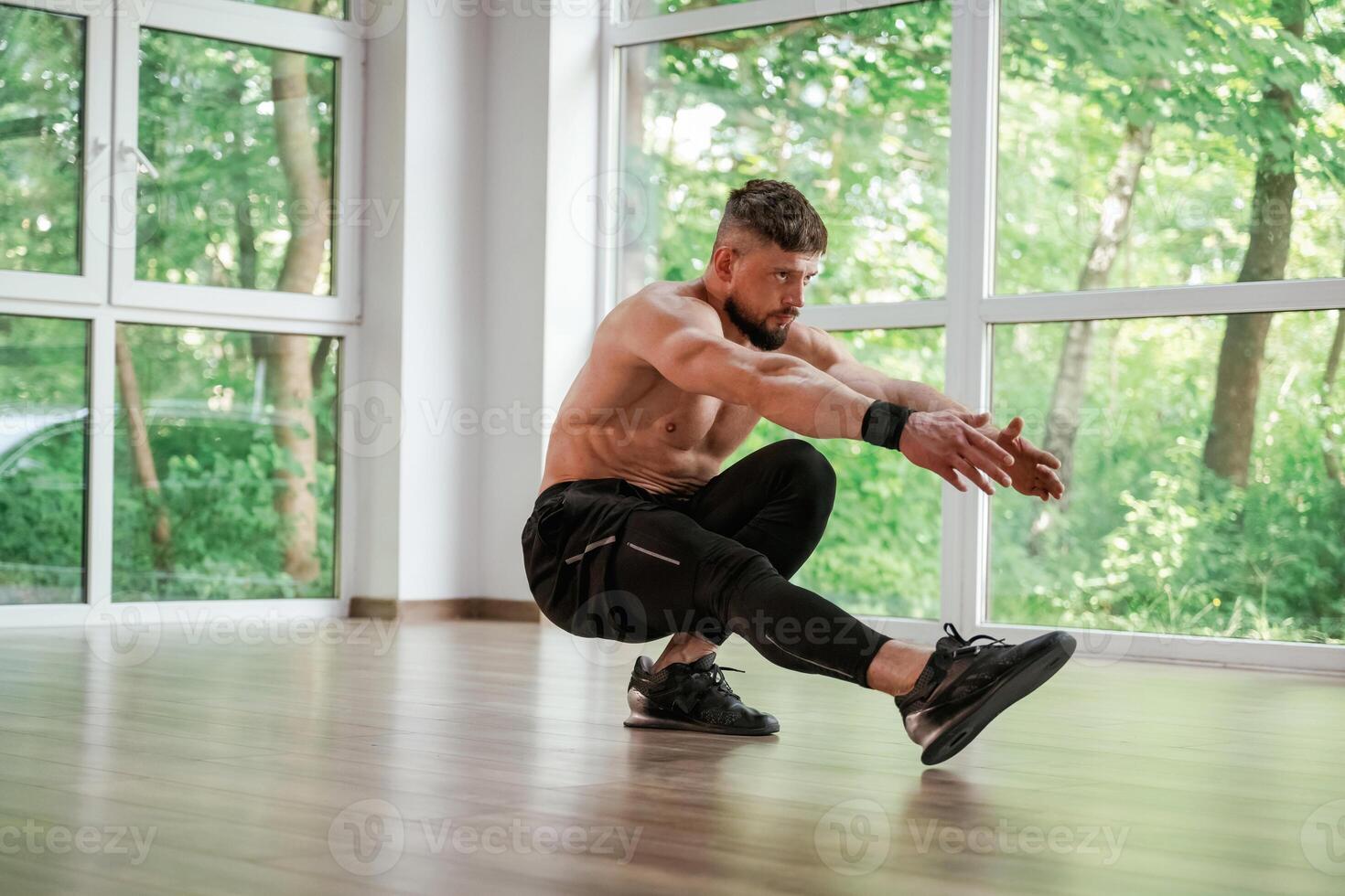 Daytime, trees ,outside the windows.. Strong muscular man is working out in the gym photo