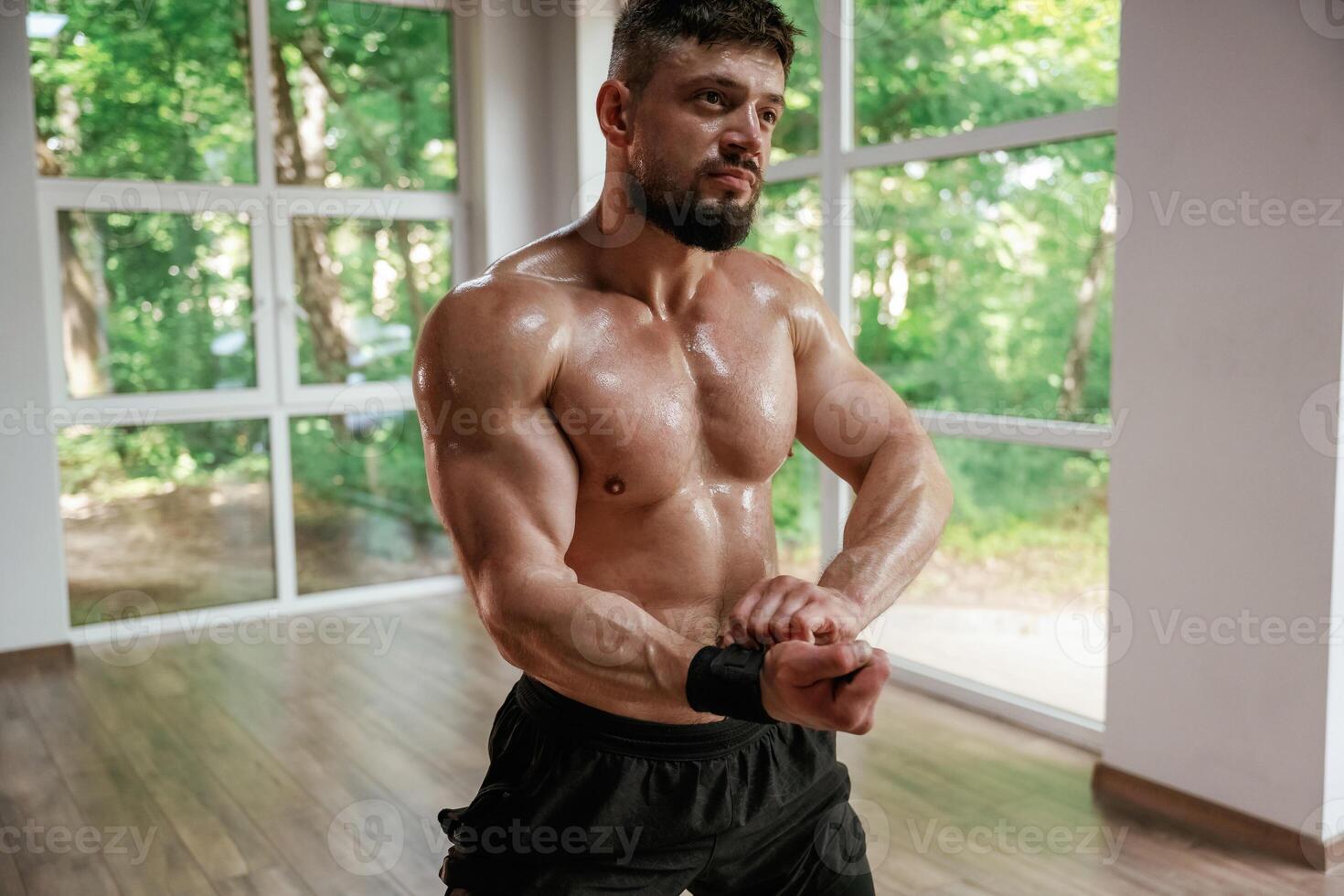 Daytime, ,trees outside the windows. Strong muscular man is working out in the gym photo
