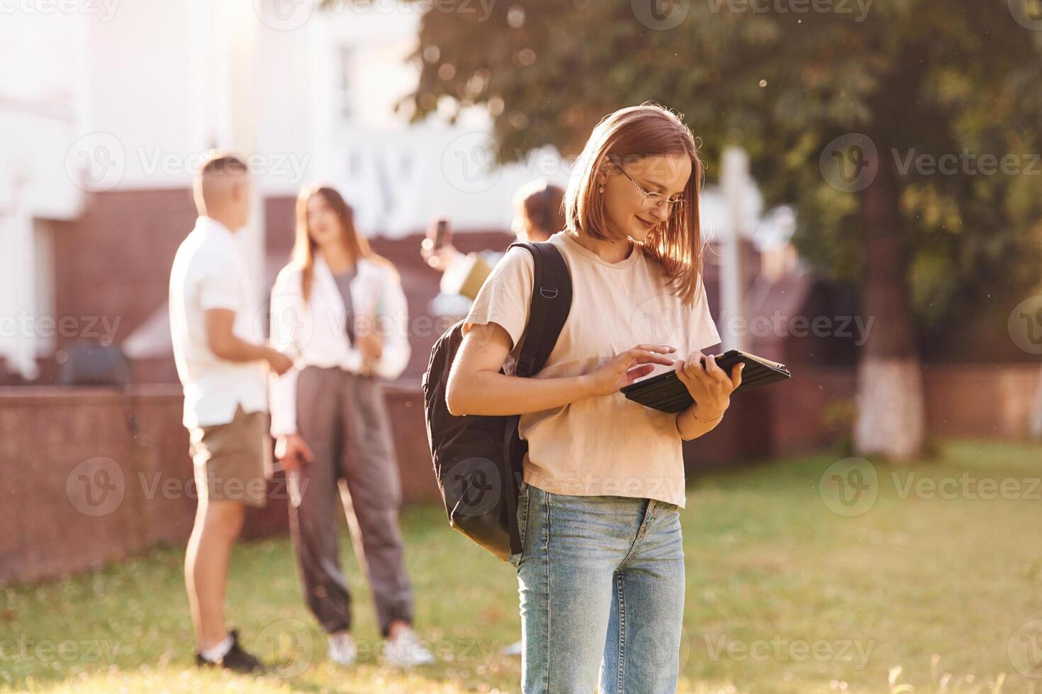 Girl is with digital tablet... Group of students are outside together photo
