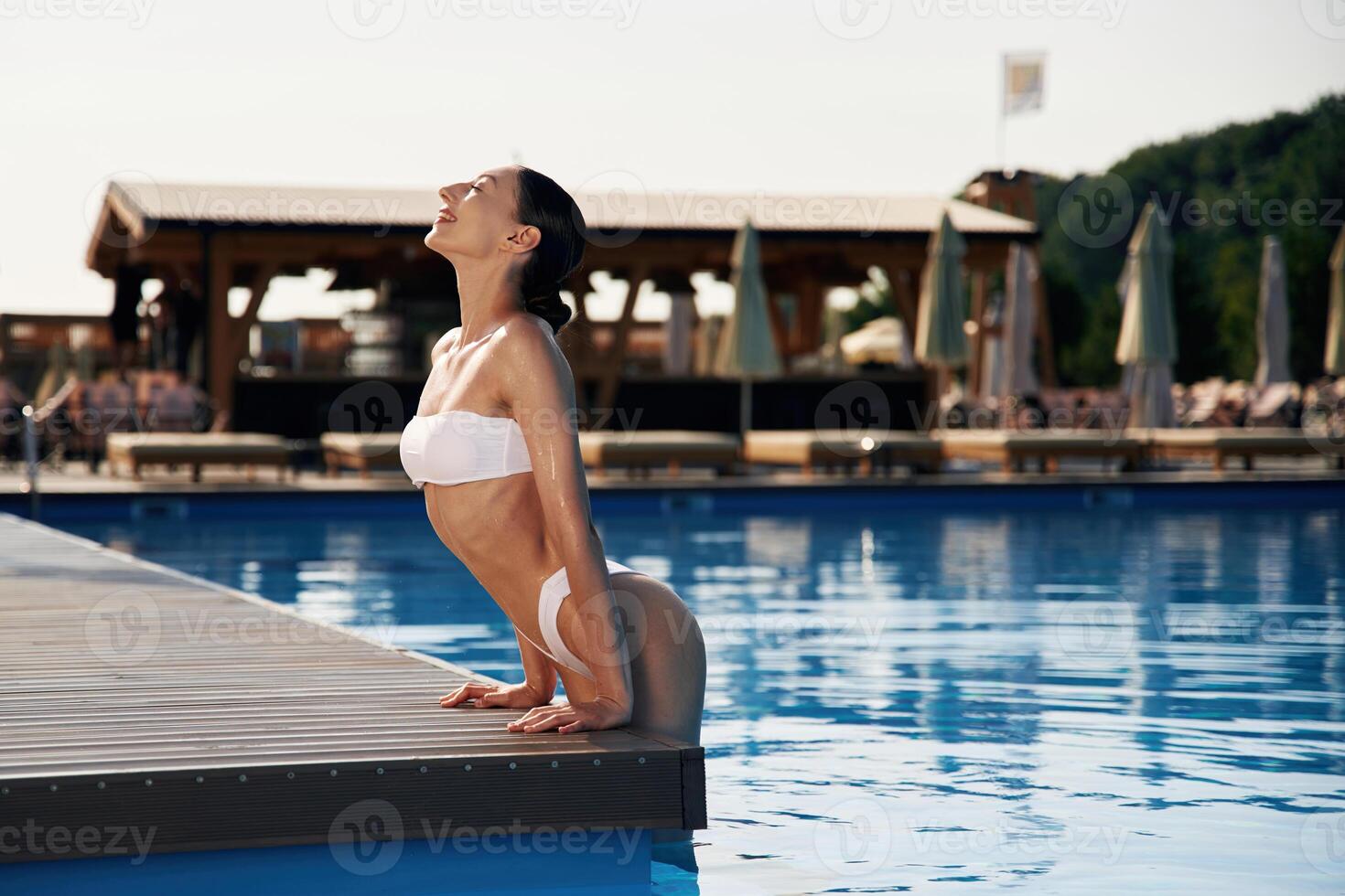 Positive, vibes. Beautiful woman, in bikini is resting by the pool photo