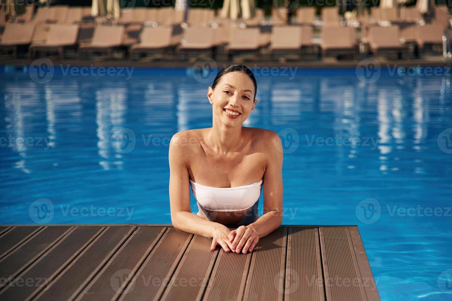 Positive ,vibes. Beautiful woman in bikini is resting by the pool photo