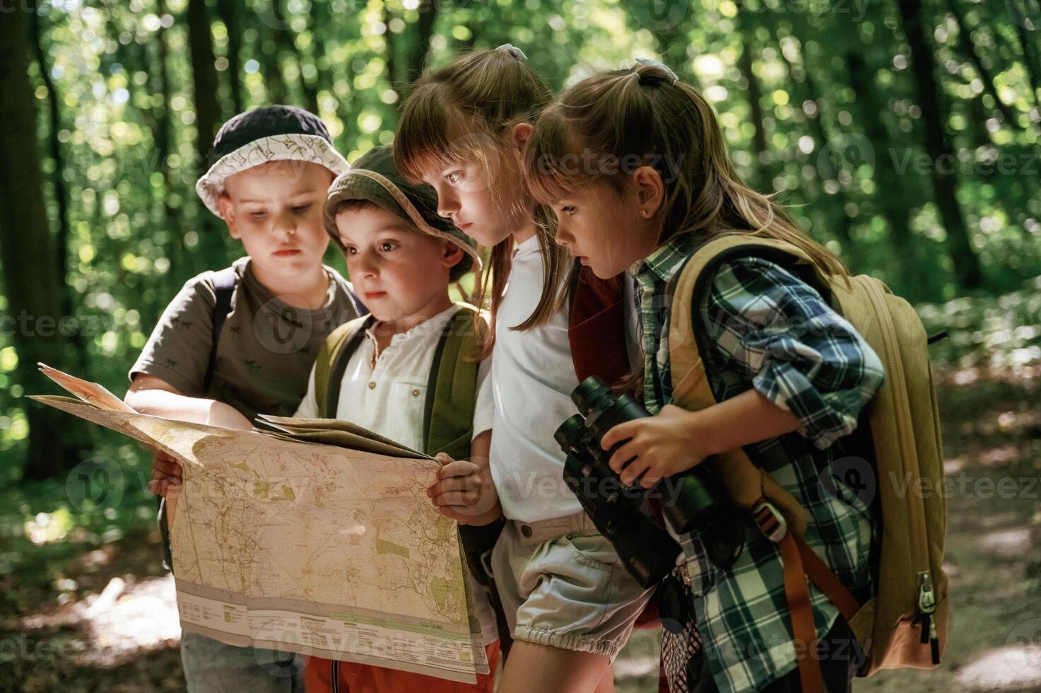 Paper map ,in ,hands. Kids in forest at summer daytime together photo