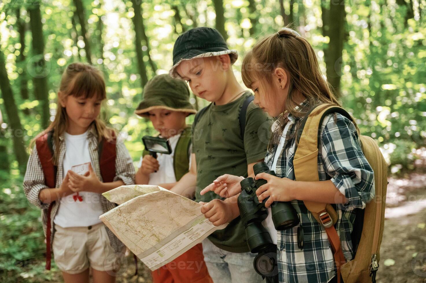 Paper ,traditional map. Kids in forest at summer daytime together photo