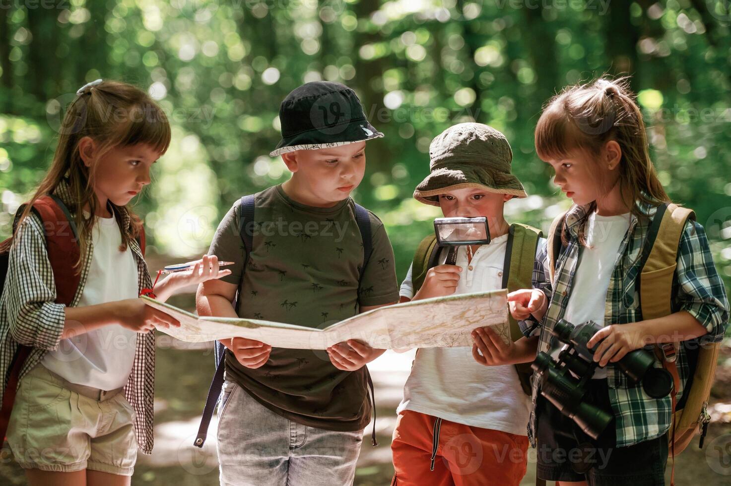 Checking, the way on the map. Kids in forest at summer daytime together photo