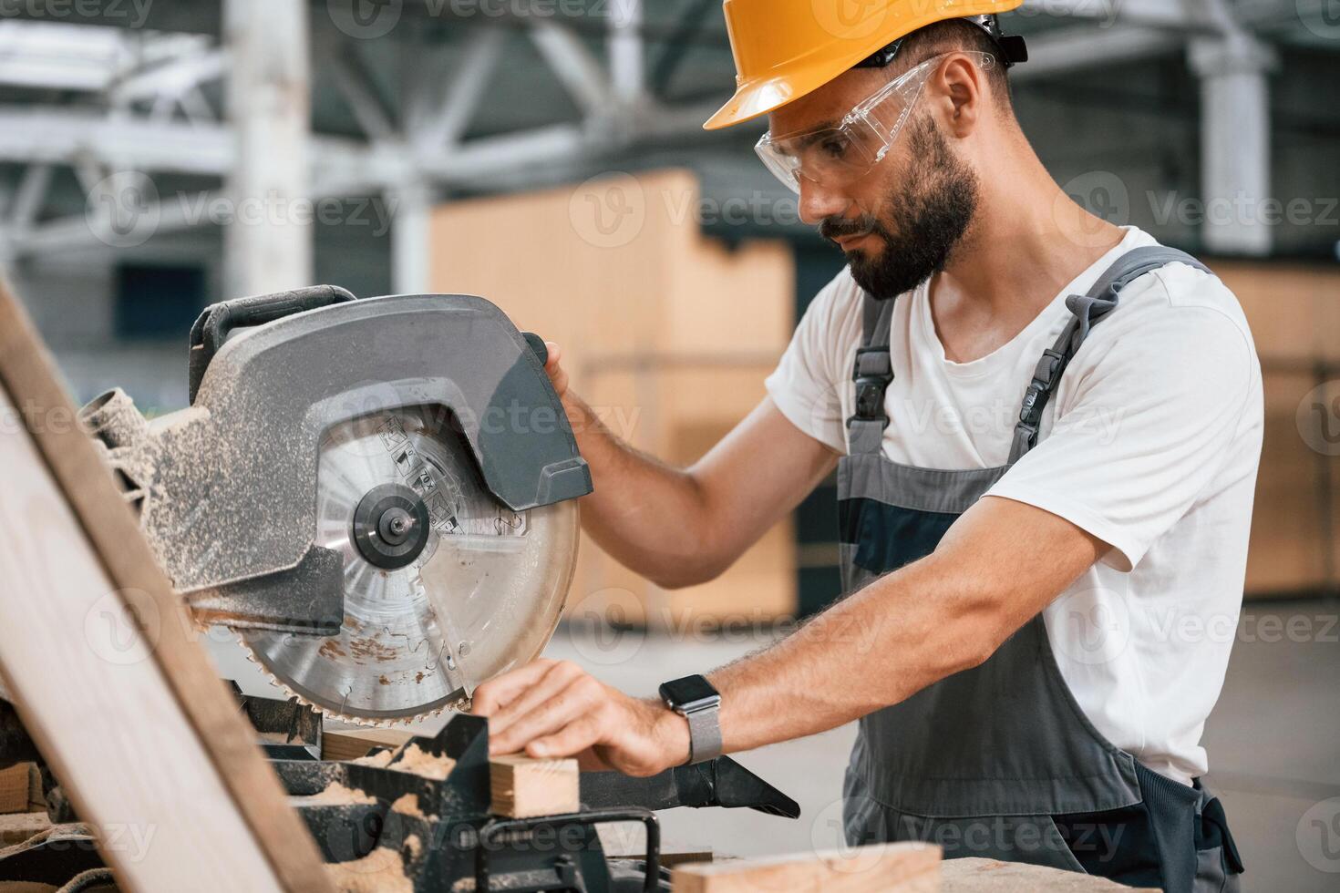 Man, is ,cutting, the wood. Industrial worker in the warehouse photo