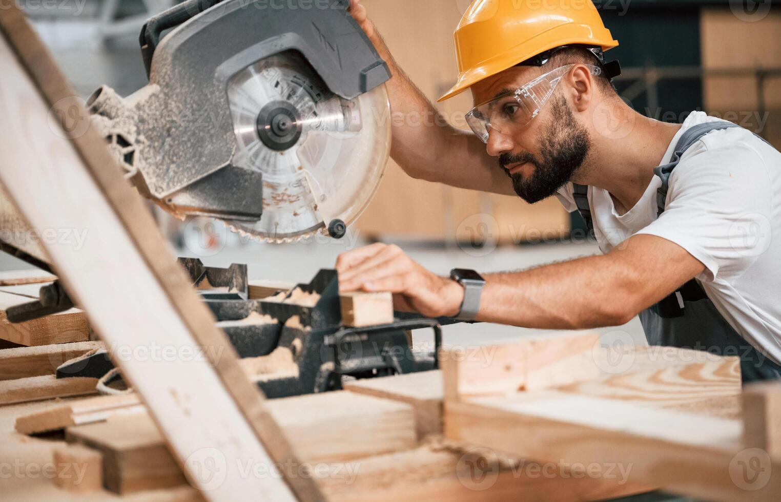 Side view, ,cutting the wood. Industrial worker in the warehouse photo