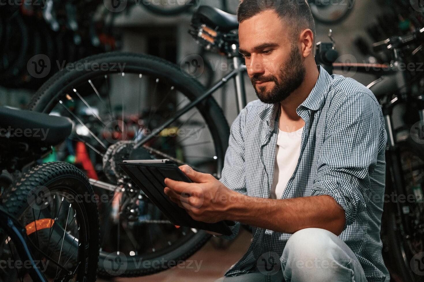 Using digital tablet. Repair man in bicycle shop, working in store.. photo