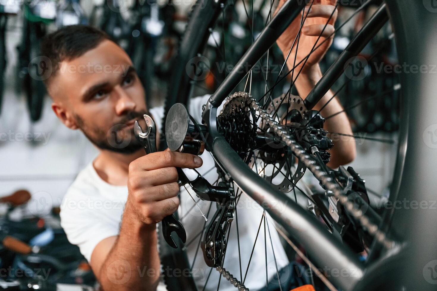 Checking the wheel and brake system. Repair man in bicycle shop, working in store photo