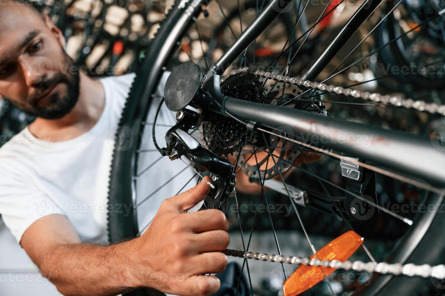 Derailleur adjustment. ,,Repair man in bicycle shop, working in store photo