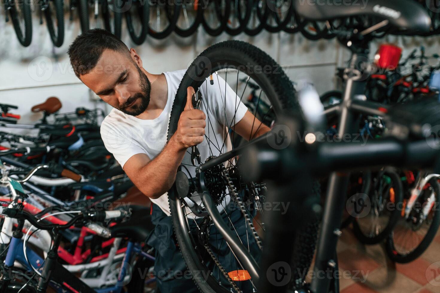 Final, adjustments.. Repair man in bicycle shop, working in store photo