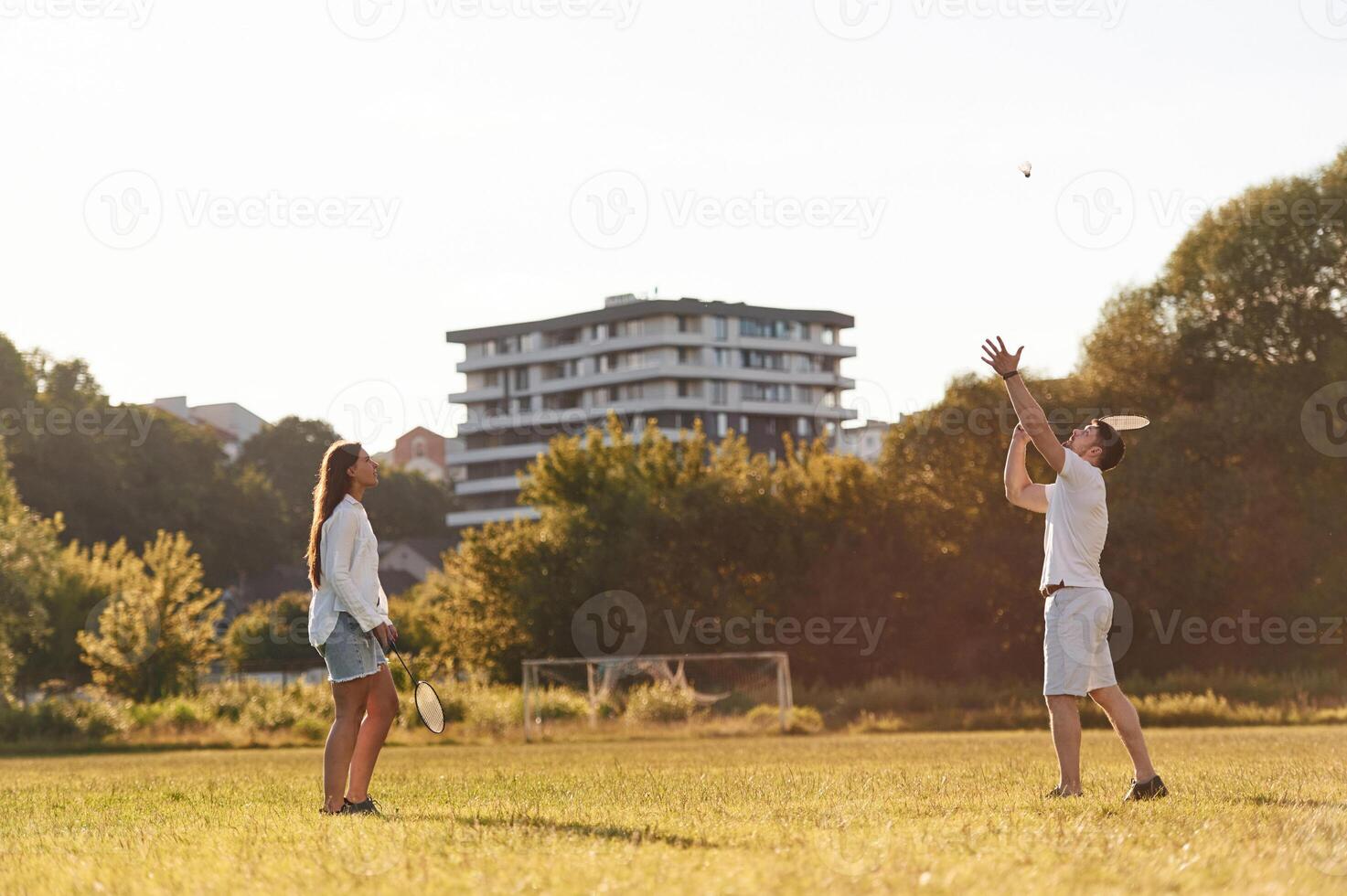 Side view... Man with ,woman are playing badminton on the field photo