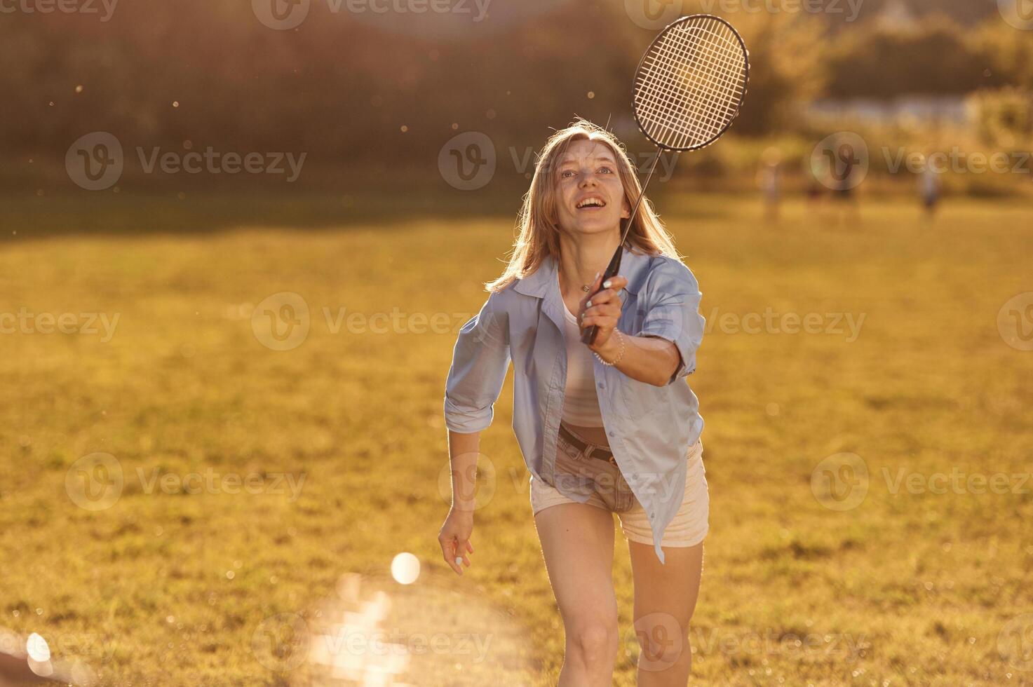 Two women are having fun, with badminton rackets, on the field photo