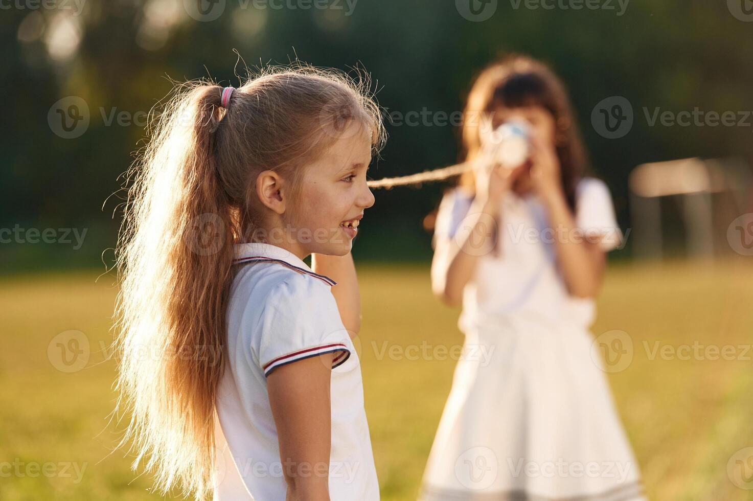 Using tin can telephone. Happy kids are on the summer field photo