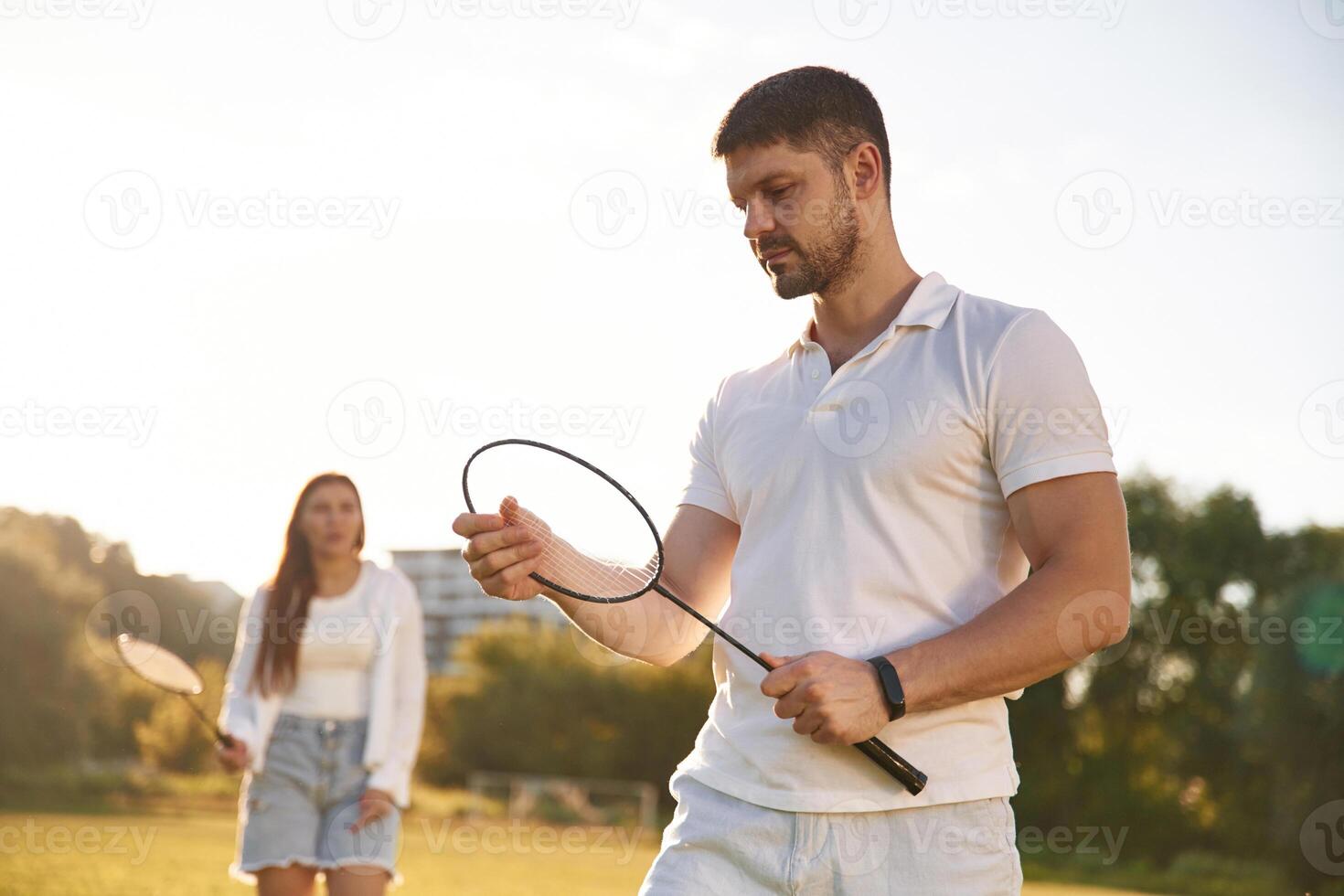 Man ,with ,woman ,are playing badminton on the field photo