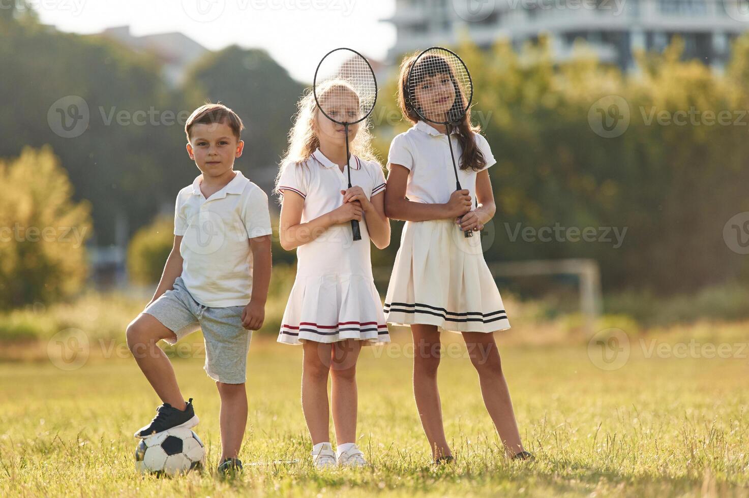 Soccer ball ,and ,badminton rackets. Happy kids are on the summer field photo