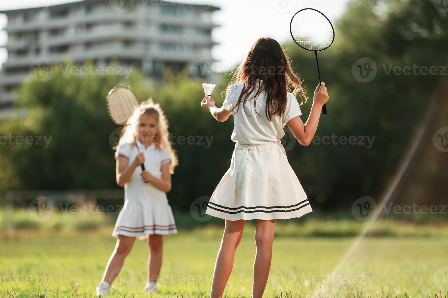 Girls are playing badminton.. Happy kids are on the summer field photo