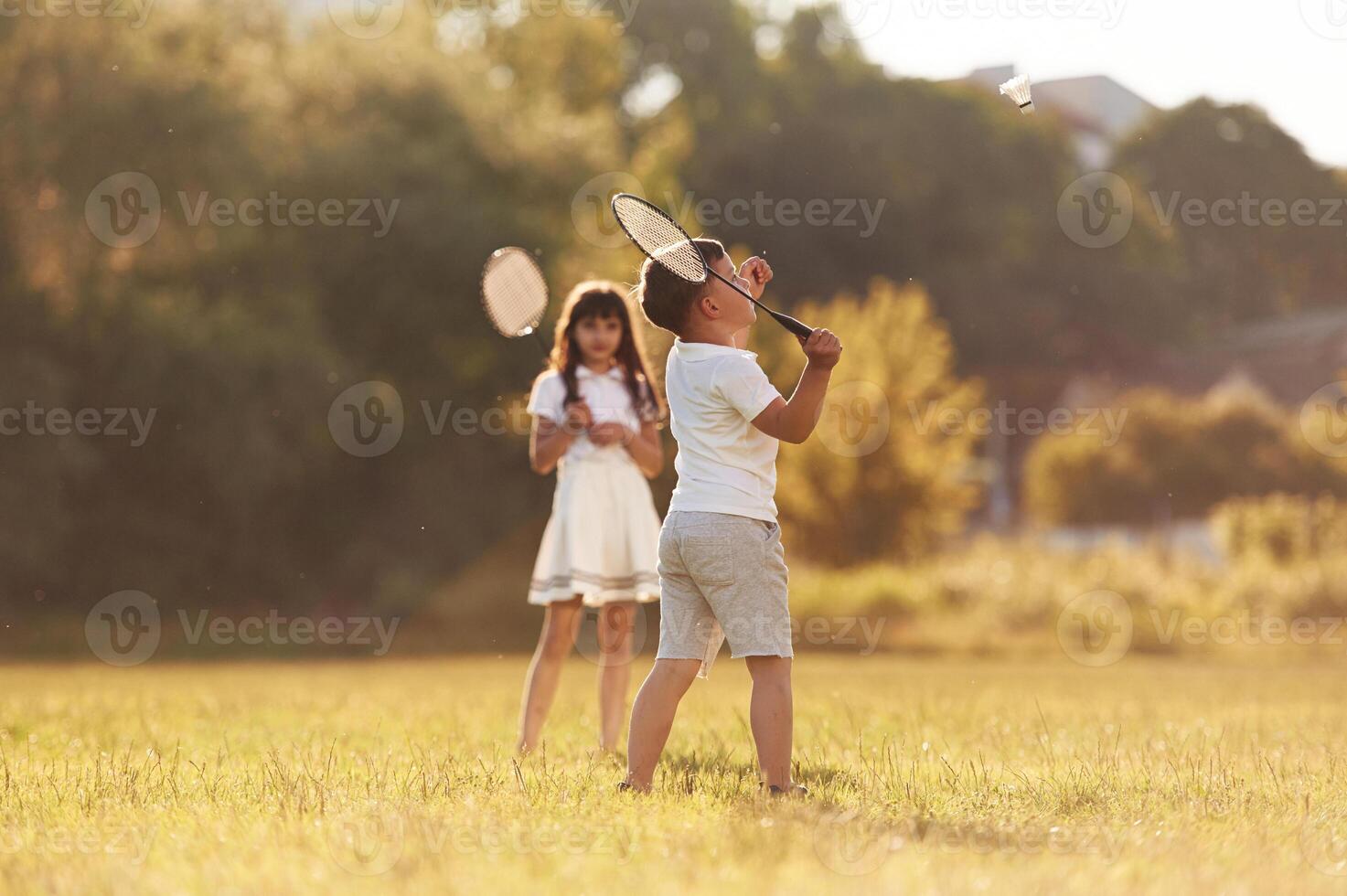 Rackets in hands,,, playing badminton. Happy kids are on the summer field photo