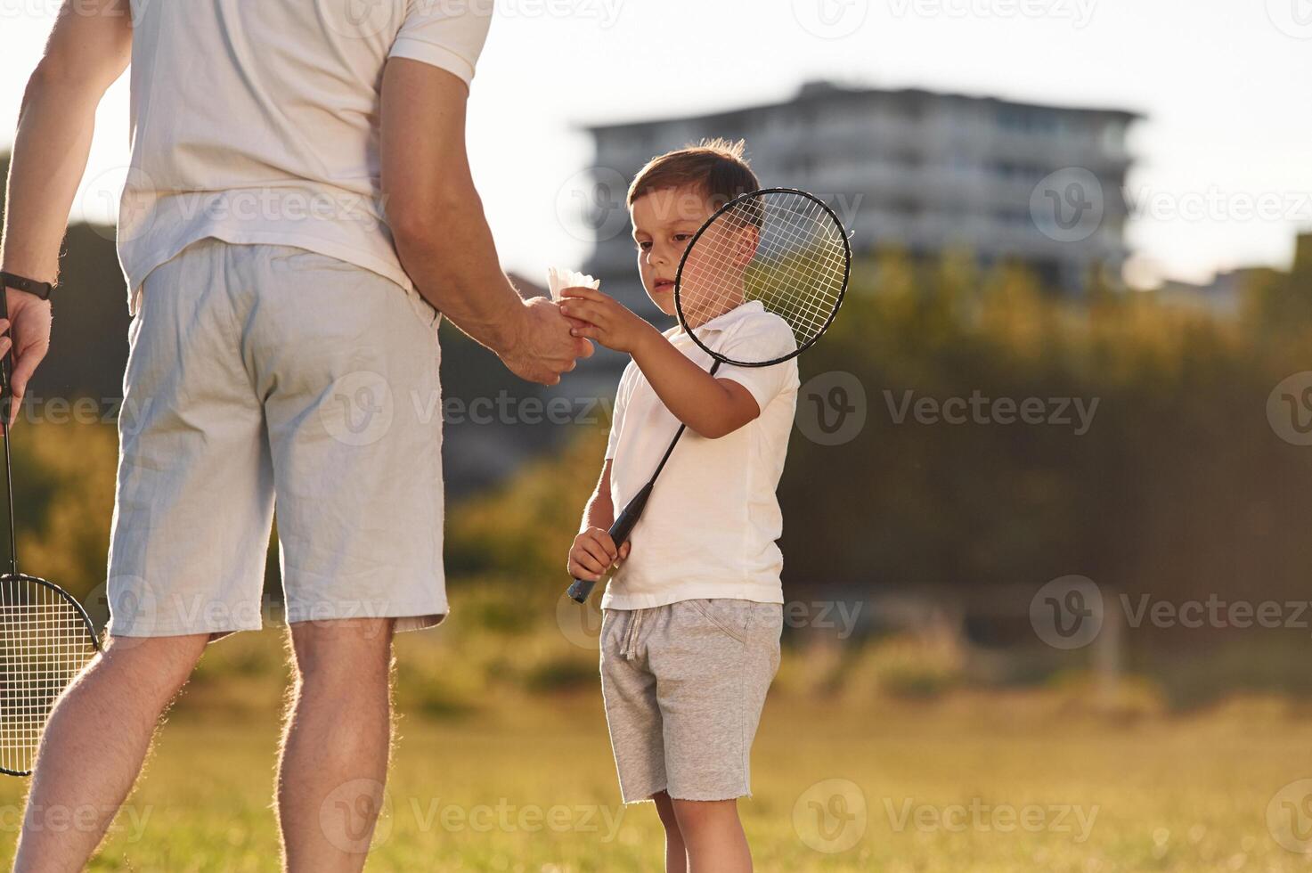 With ,badminton rackets.. Father and little son are together on the summer field photo