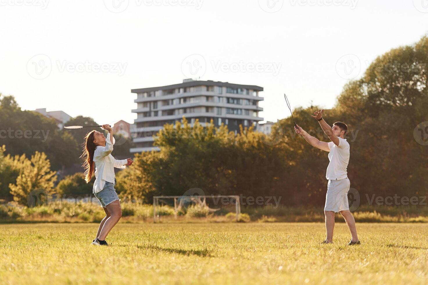 Side view... Man with woman are playing badminton on the field photo