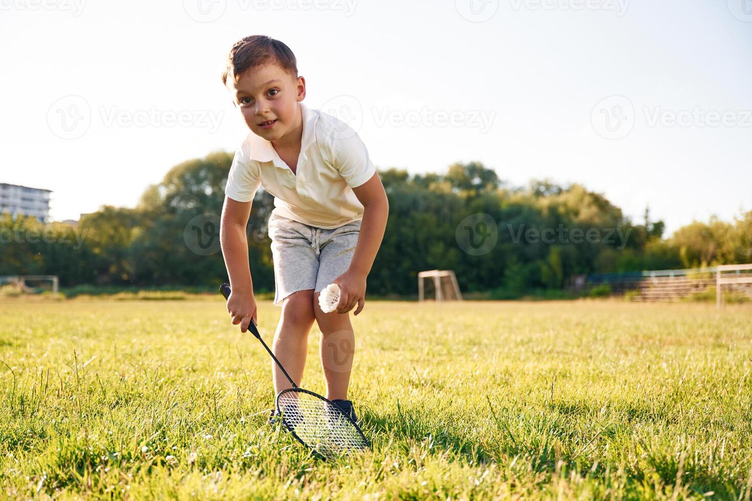Happy little boy is with two tennis rackets on the summer field photo